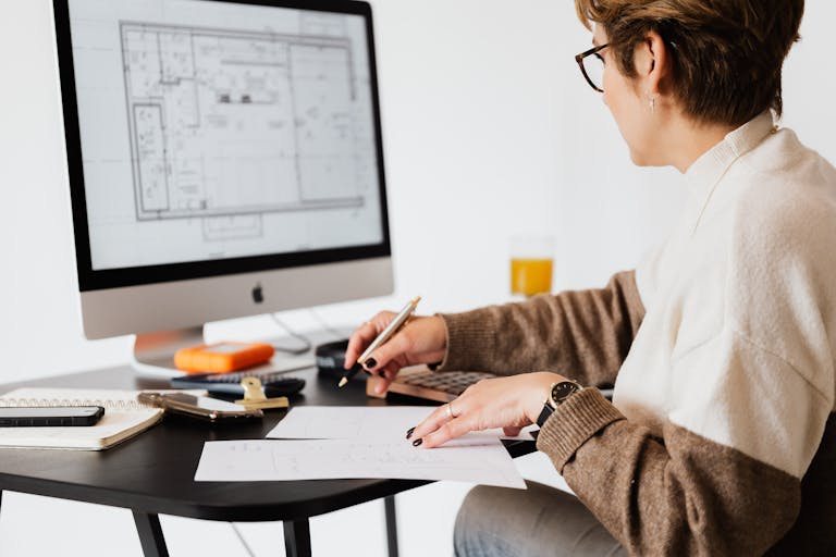 Plan your online business of a Woman designing architectural blueprints using desktop computer in a modern office setting.